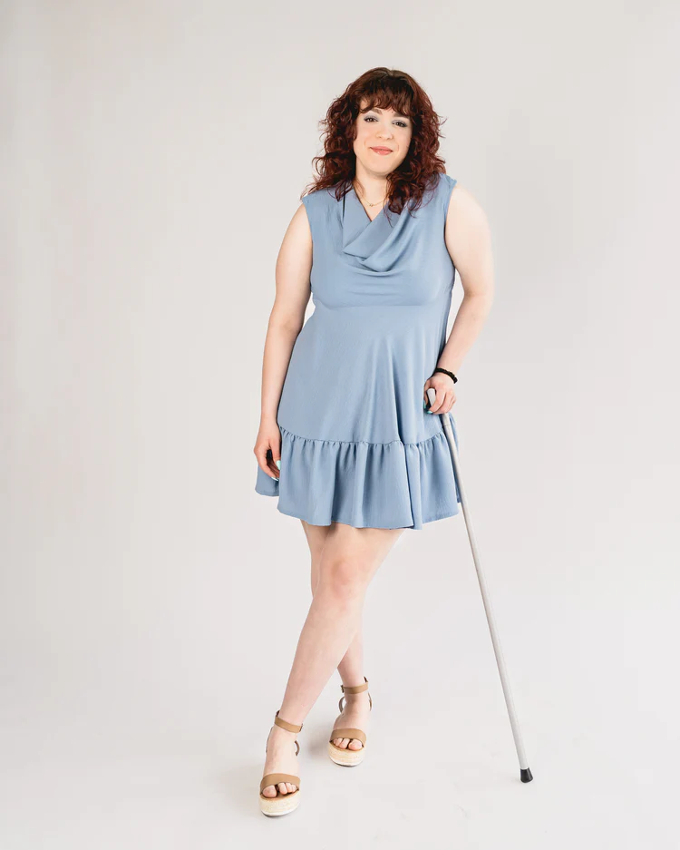 Woman with walking stick wears blue Babydoll dress with snap closures